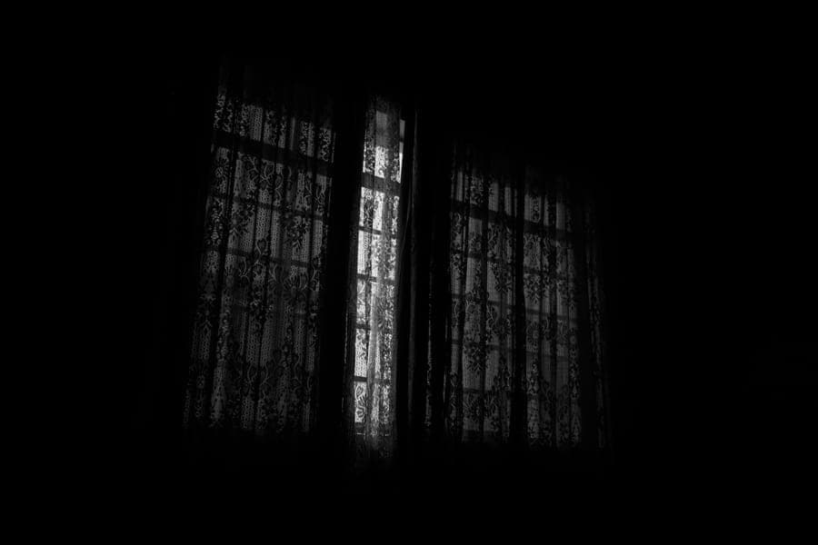Curtains drawn across a darkened bedroom window