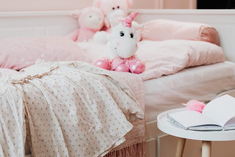 A small child's bed with a blanket in a bedroom